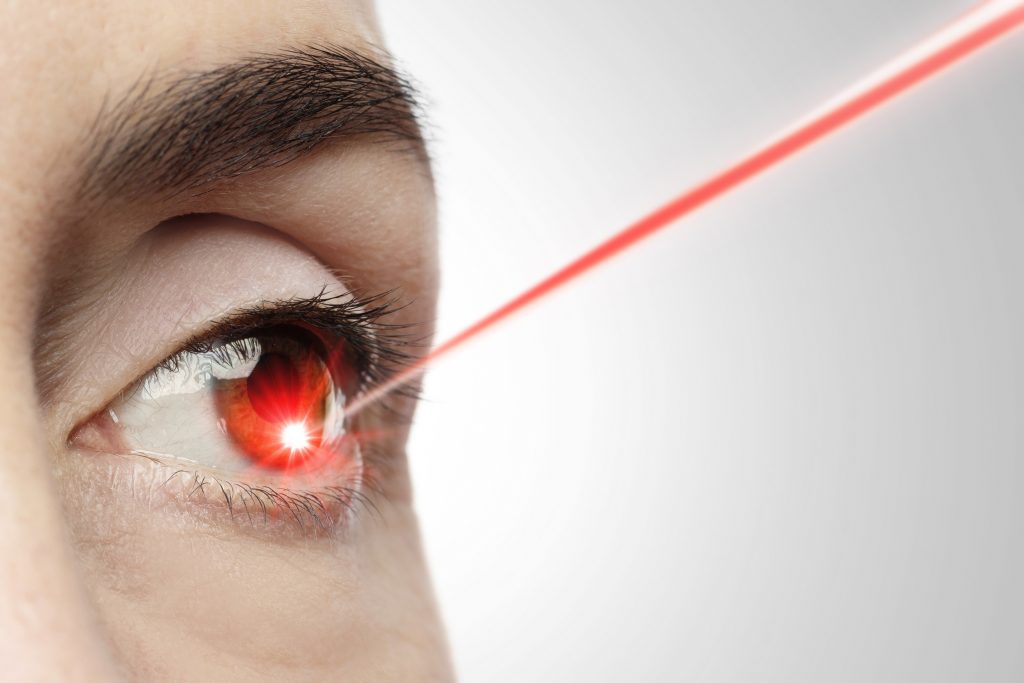 Female eye with a laser beam pointing into the iris